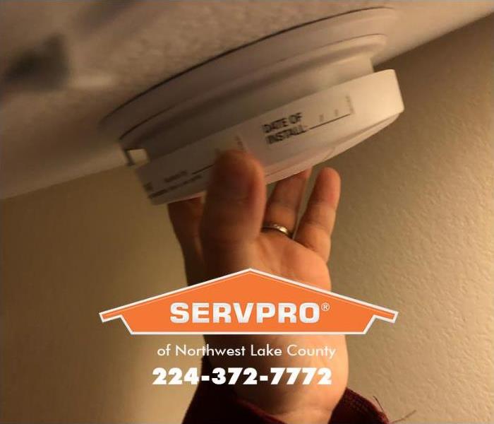 A person is replacing a smoke alarm.